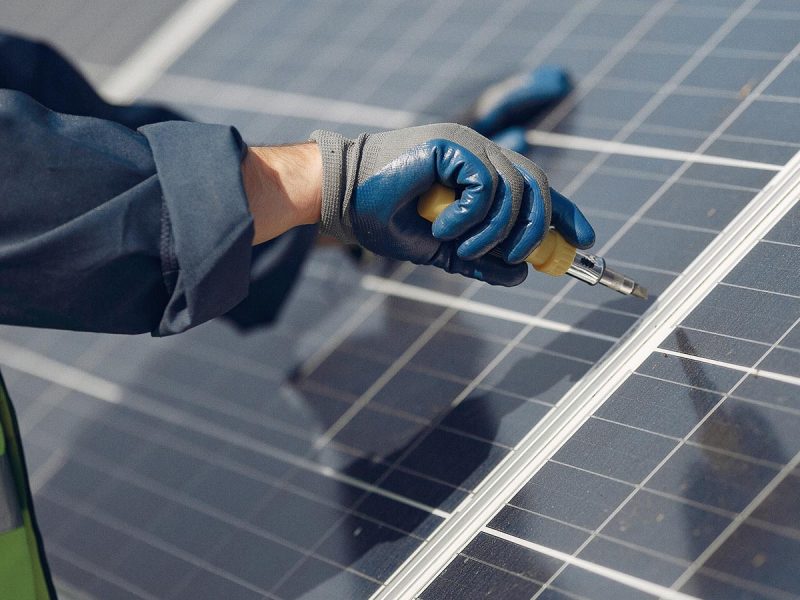 Man in a white helmet near a solar panel